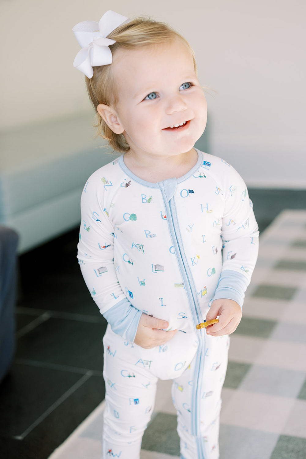 A white and blue long-sleeved baby sleep romper with a golf-themed print, featuring a zip down the front and blue cuffs.