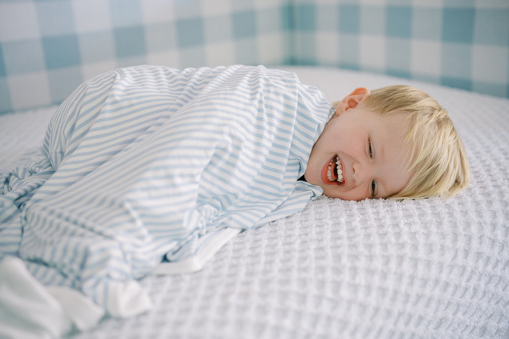 A stack of folded striped blankets in blue, pink, and green, arranged vertically with the striped patterns visible.