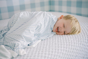 A boy cuddled in a blanket and smiling. 