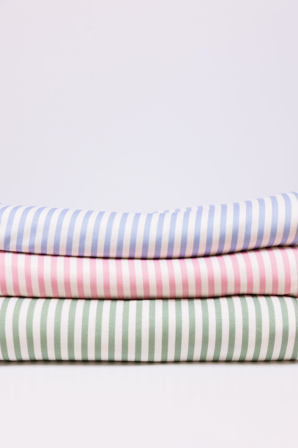 A stack of folded striped blankets in blue, pink, and green, arranged vertically with the striped patterns visible.