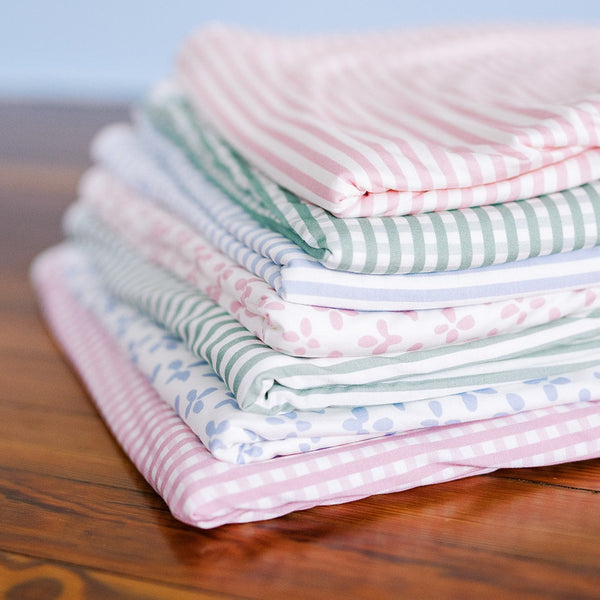 Variety of blankets folded on a wood table. 