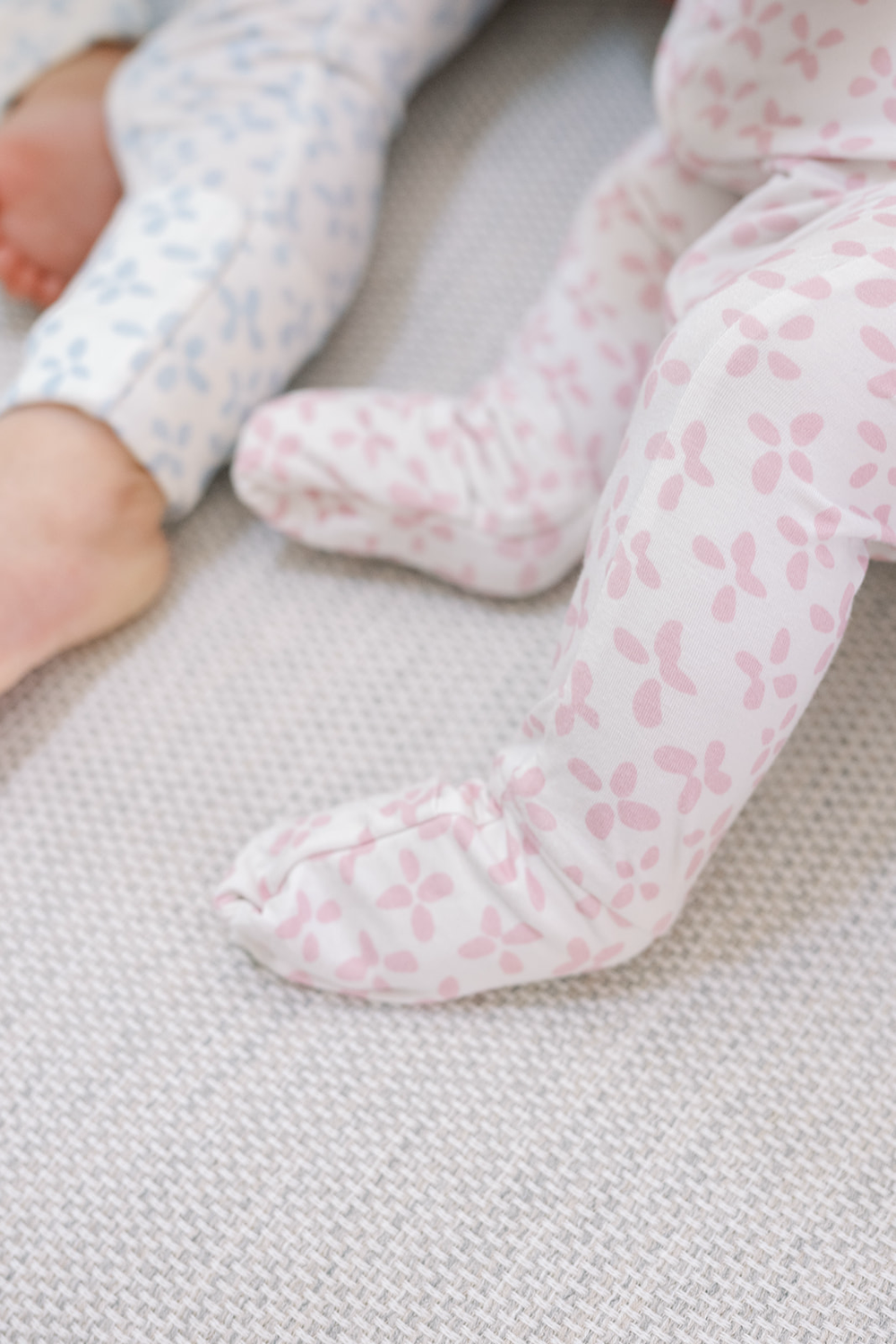 A long-sleeved sleep romper with a floral pattern, buttoned at the top, designed for infants.