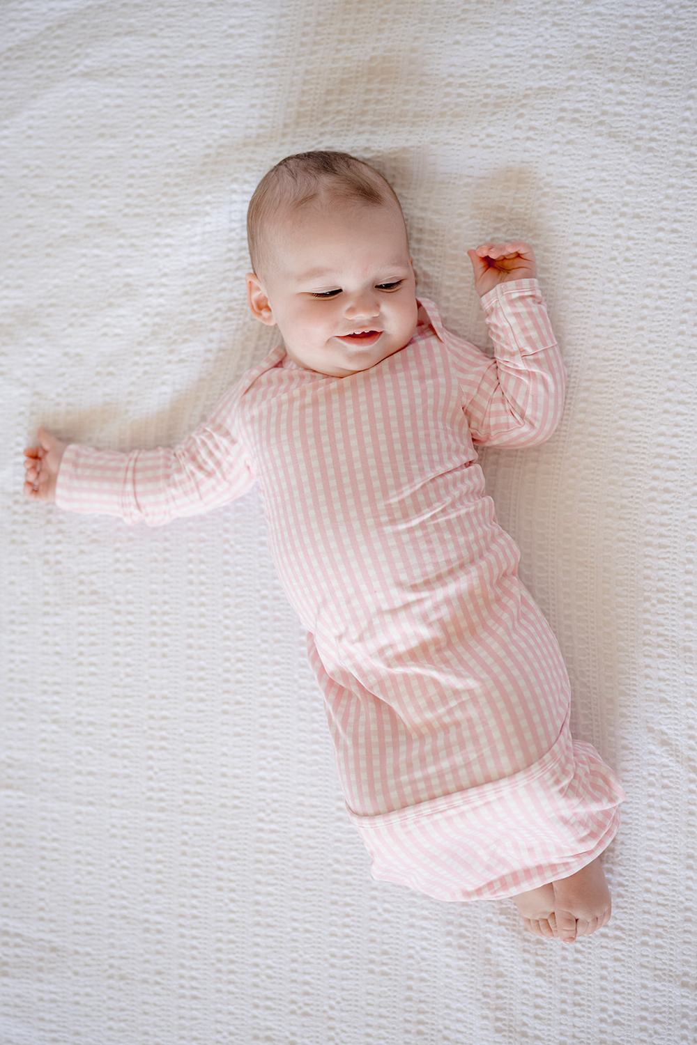 A pink gingham newborn gown with long sleeves.