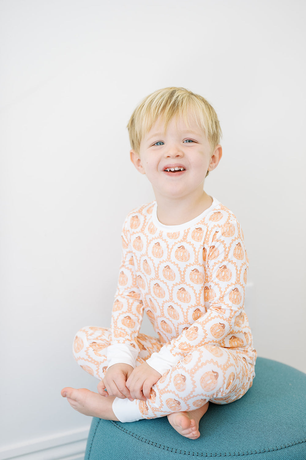A two-piece pumpkin-shaped pajama set for toddlers, with orange and white colors and pumpkin patterns.